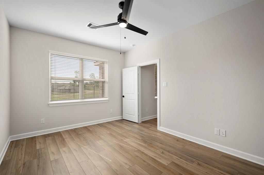 The primary bedroom exudes sophistication with luxurious vinyl plank flooring and a sleek modern ceiling fan.