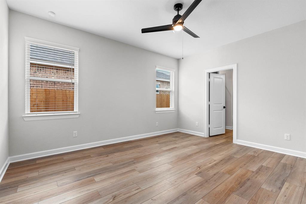 In the primary bedroom, vinyl plank flooring creates a foundation of modern elegance, while a ceiling fan provides a soothing breeze on warm nights