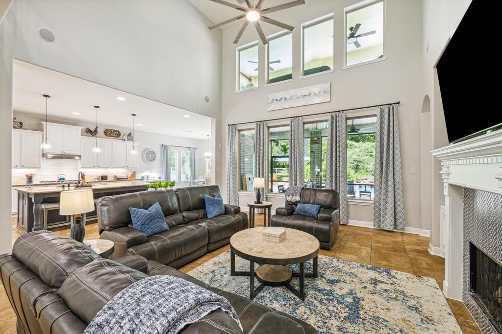 Modern living room with high ceilings, large windows and open kitchen layout. Elegant, inviting, and well-lit space.