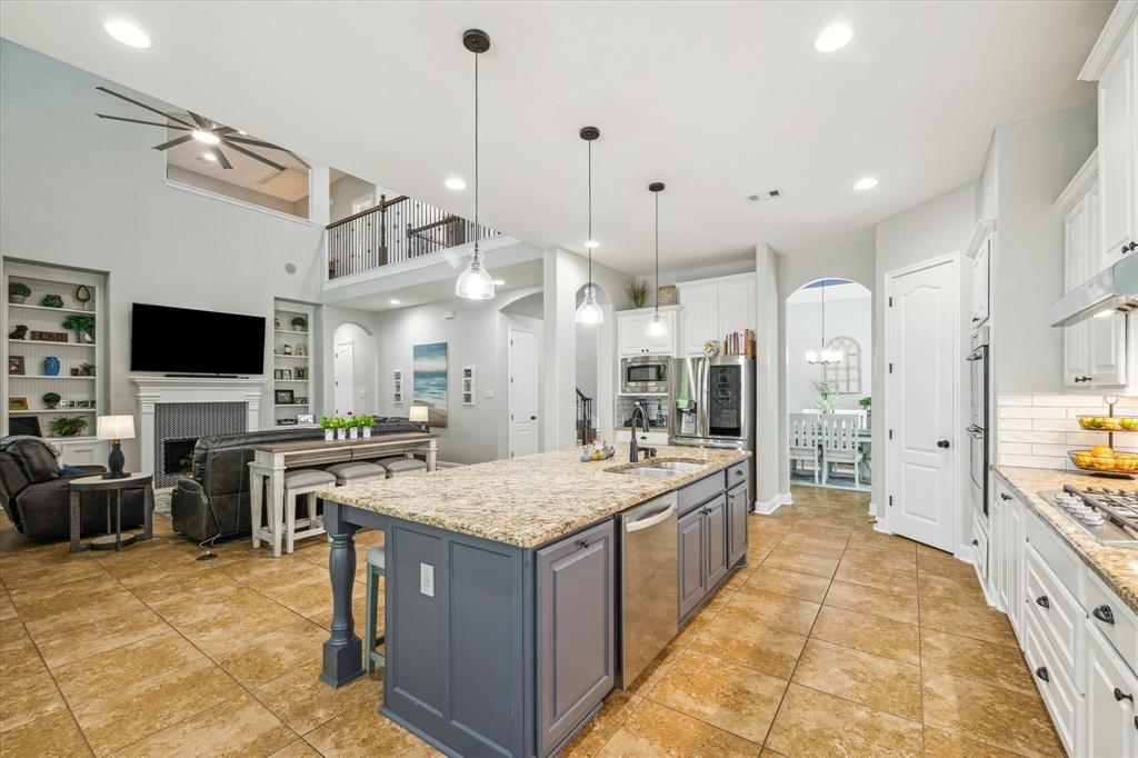 Modern open-plan kitchen and living space with neutral colors, high ceiling, tiled floors, and a mix of classic and contemporary design elements.