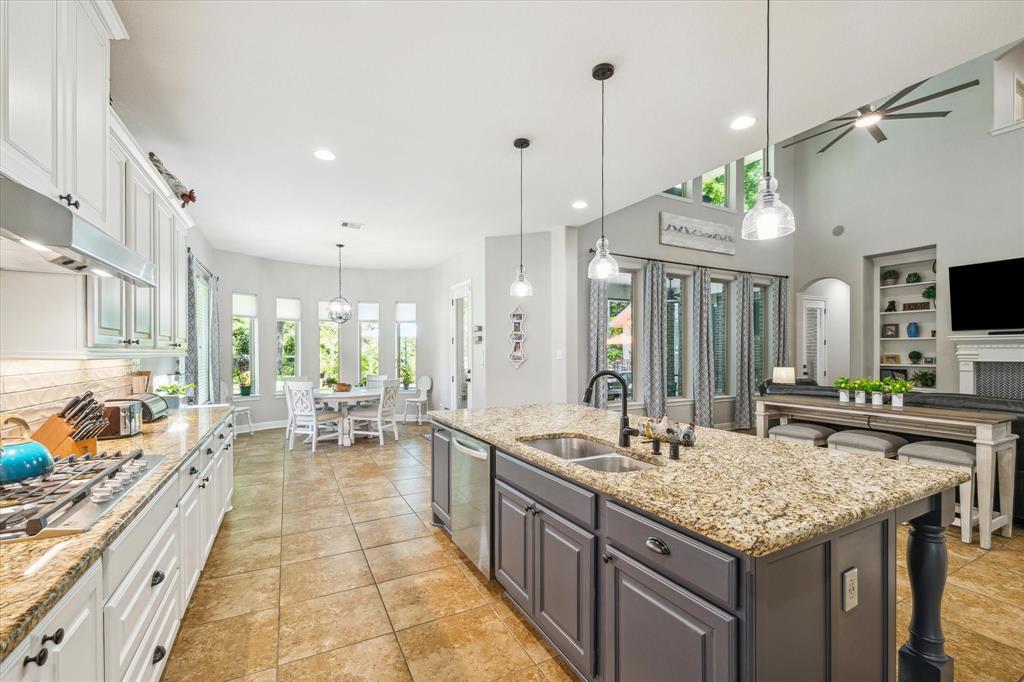 Bright, spacious kitchen with a central island, modern appliances, granite countertops, and a dining area with ample natural light.