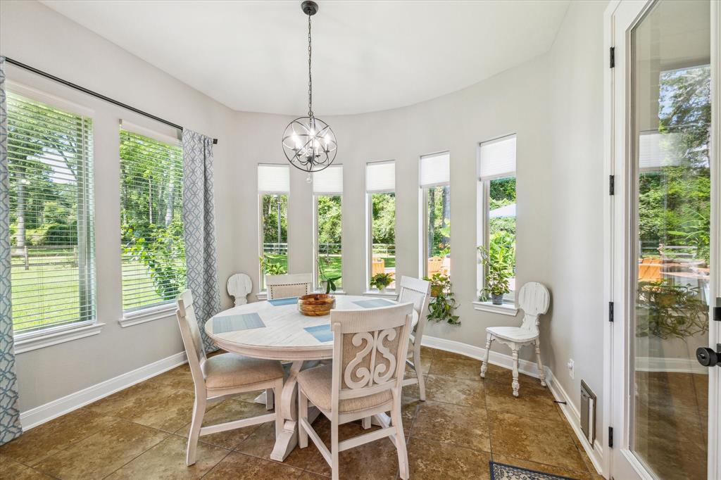 Bright breakfast area with tiled floors, large windows and a garden view and pool area.