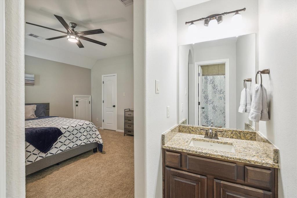 En-suite bathroom with neutral colors and granite countertop vanity.