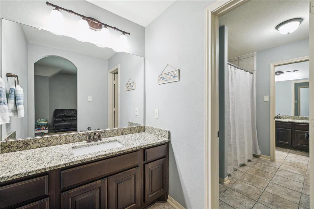 Well-lit bathroom with a large mirror, granite countertop, tiled floor, Jack and jill bath for bedrooms 4 and 5