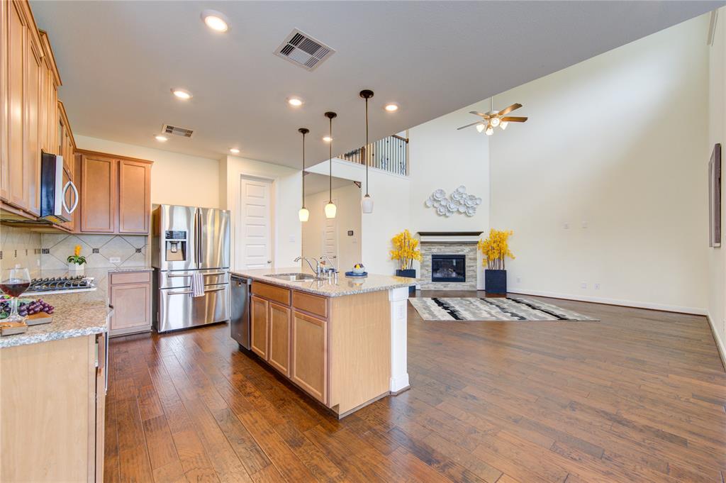 The island with sink as well as additional seating also has the stainless steel dishwasher and pendant lighting over  the island.