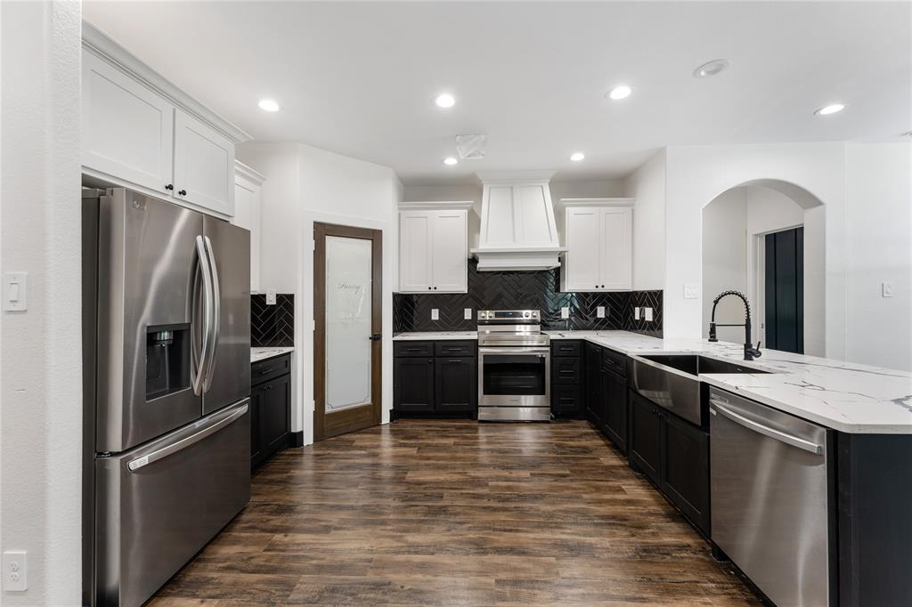 Refrigerator, large farmhouse sink, black lower cabinets and white uppers give a wow factor.