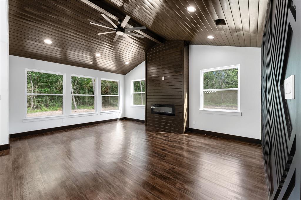 This room has a wow factor with wood plank ceilings, fireplace, wall of windows, recessed lighting, and extra large ceiling fan.