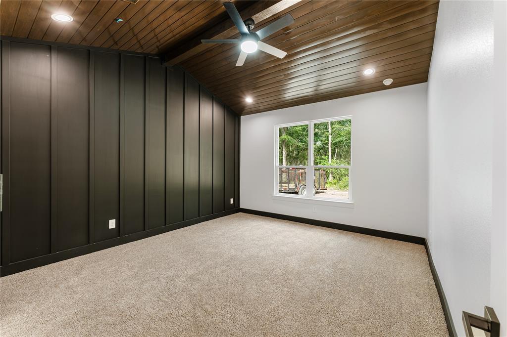 Spacious primary bedroom has vaulted, wood slat ceilings and a wood beam.