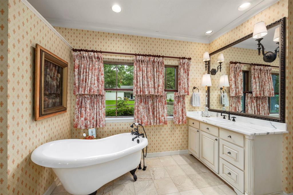 Primary bathroom with one of two marble top vanities shown, soaking tub and natural light.