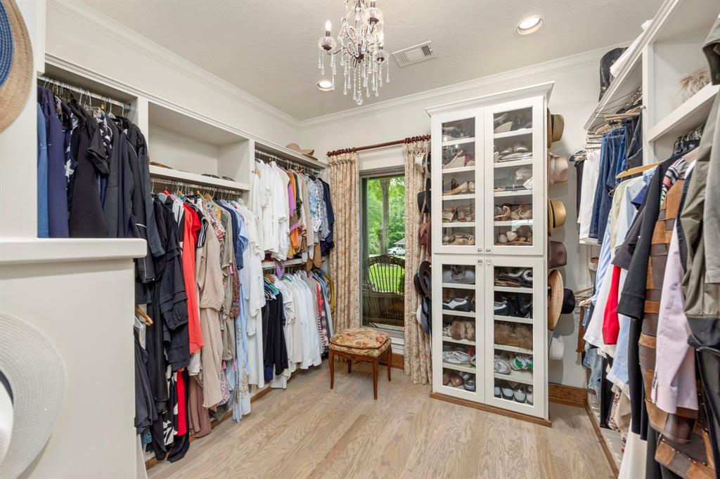 One of two separate walk-in closets. This special space includes built-in enclosed glass front storage, plenty of shelf space and accommodates short and long hanging items.