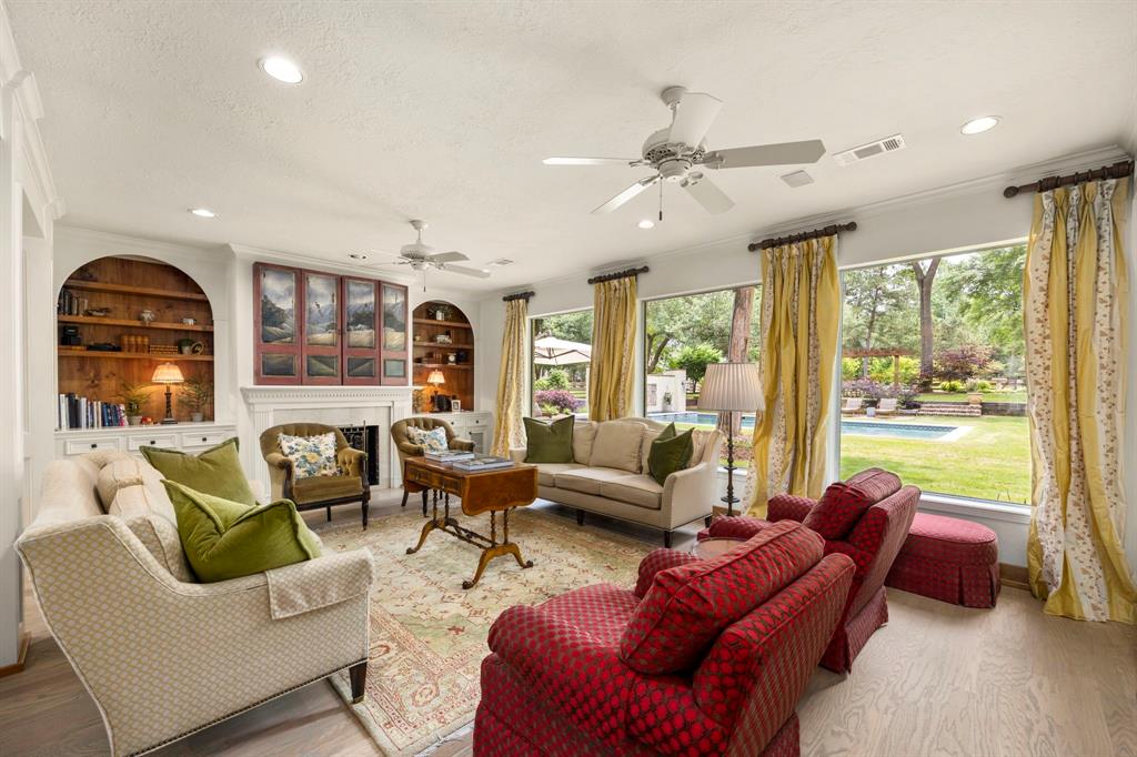 Generous living area with gorgeous fireplace (TV tucked behind the decor cabinet above*), built-in display area, a wall of oversized windows allows for optimal natural light and beautiful views of the backyard, custom draperies & surround sound included.