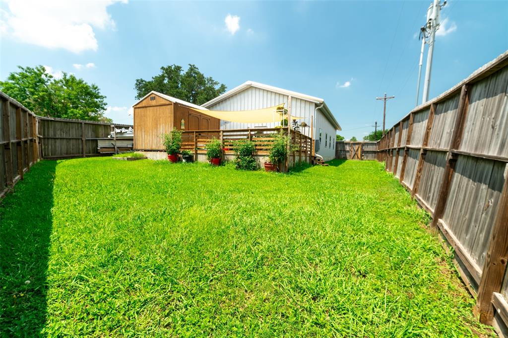 1610 N. Park St back yard with tall full fencing and healthy grassand an access on both sides of the house.