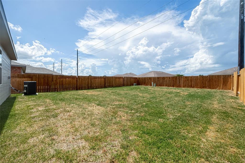 A spacious backyard with green grass and wooden fence.