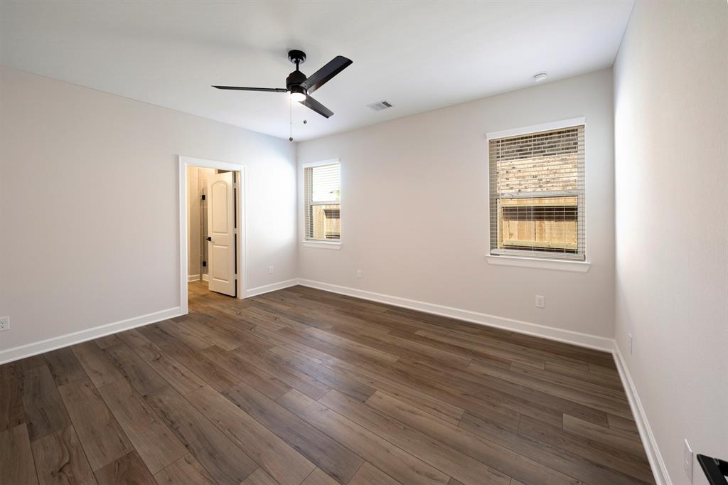 The primary bedroom is a sanctuary of comfort and tranquility, adorned with durable vinyl plank flooring and cooled by a gentle ceiling fan overhead.