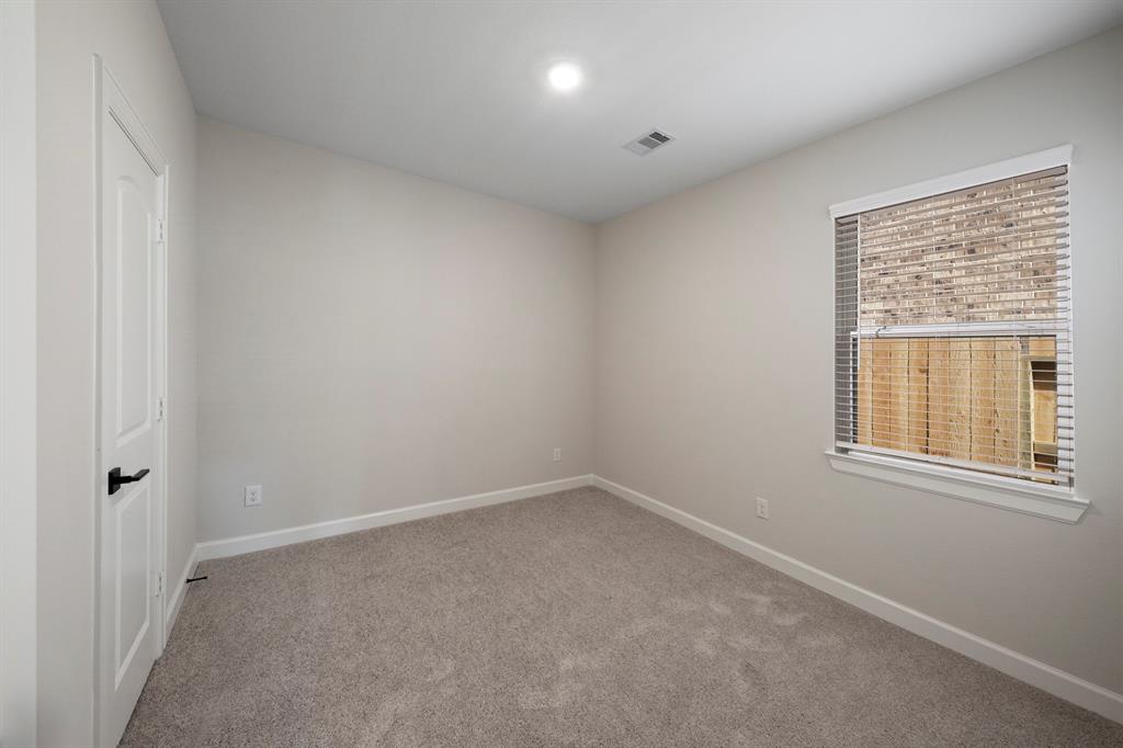 In the secondary bedroom, a window provides a glimpse into the surrounding scenery, infusing the space with brightness and warmth.