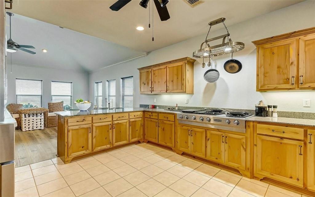 The kitchen is a culinary dream. Huge Kitchen with Pot rack, Jenn-Aire cooktop, custom cabinetry and upgraded lighting!