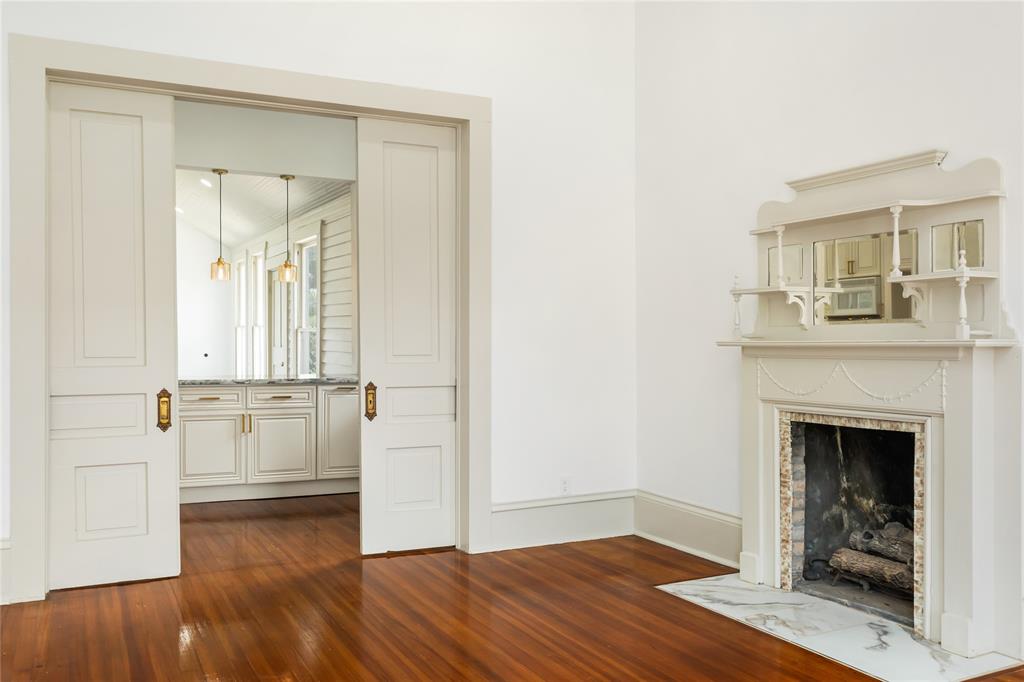 Front living area with wood burning fire place and refurbished wood flooring showing double sliding doors to the kitchen