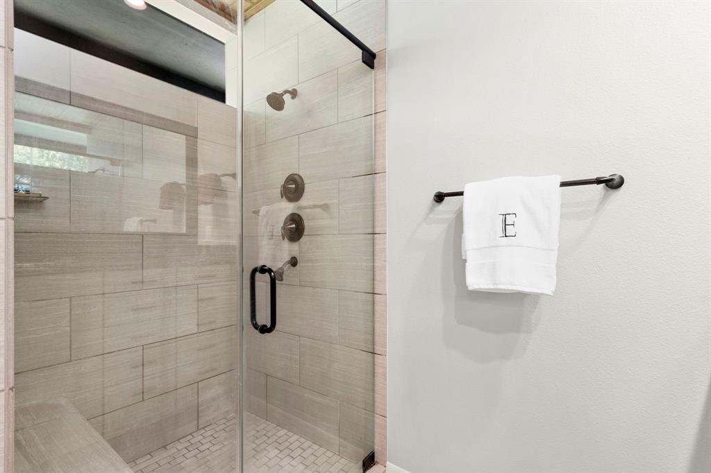 Updated super sized walk in shower with bench seating and beautiful tile surround.