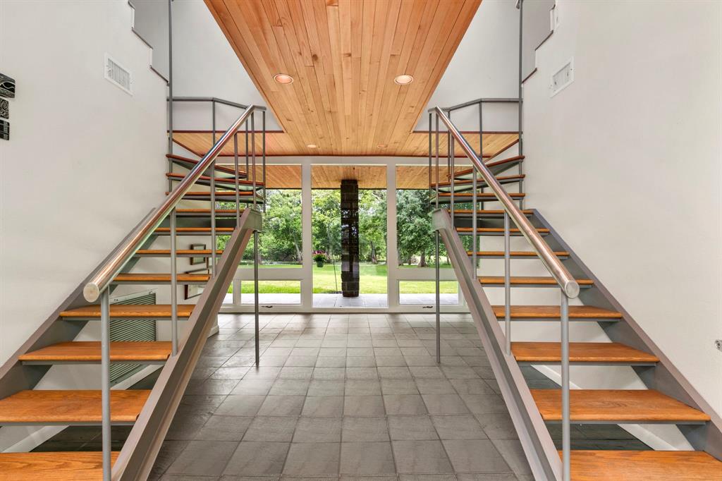 Grand foyer with dual staircases is sure to impress your guests. Spectacular views of the acreage are seen through the walls of windows across the entire back of the home.