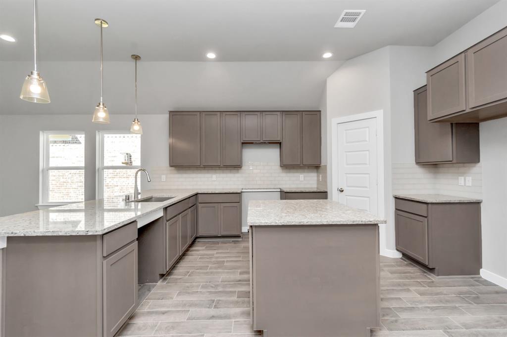 Discover another perspective of this stunning kitchen, generously appointed with an abundance of counter space. Sample photo of completed home with similar floor plan. As-built interior colors and selections may vary.