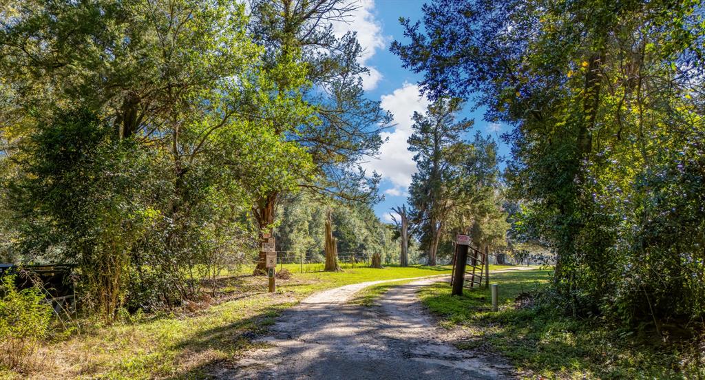 66-acre tract in Splendora ISD. There is an old homesite on the property that has been recently occupied. There is a newer medal shop. Home site sets far off the road down a dirt driveway and is very high and dry. It is a beautiful place for your dream home with your porch looking out over 15 acres of cleared pastureland. The remaining acreage has mature hardwoods. There are two large ponds on the property and the property borders Peach Creek on the South side. There are a few outbuildings for storage. This size land is rare in Splendora ISD, and the privacy is amazing.