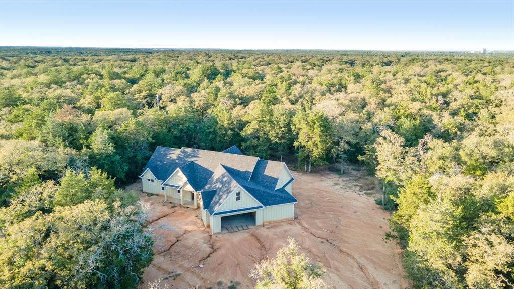 Central to Austin, Waco, Brenham and Bryan/College Station, this 3 bedroom 2 bath home with extensive covered porches and outdoor kitchen with fireplace is sure to be a dream with the right finish out. The home is nestled in the middle of 20 wooded acres and sits on one of the high points of the property. Construction began in 2024 with slab, framing, roof, cement board exterior walls and windows installed. This is a rare opportunity to start with a blank slate. A quiet country location that feels like you are in the middle of nowhere - just the bees, the birds, the wildlife and your soon to be dream home. Ag valuation in place with heavy woods ready for exploring.