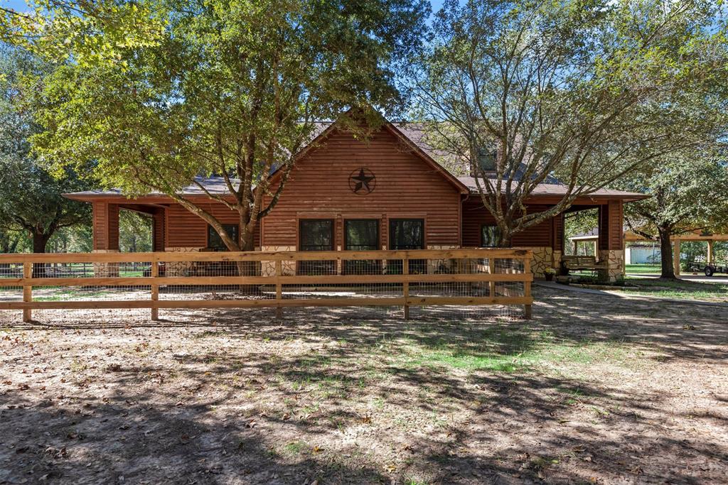 Nestled in the heart of the countryside, this delightful log cabin-style home is a true hidden gem. Tucked away on a partially wooded 3.11-acre lot with a shared pond, this haven offers 4 to 5 bedrooms & 4 full baths, including a beautifully updated primary bath. The spacious 37x45 workshop, with a 17X40 covered area, is ideal for projects or storage, while a 3-car carport adds convenience. Inside, you'll find a warm & inviting layout with a wet bar perfectly situated by the dining area & kitchen for entertaining. Upstairs, a game room & media room provide endless fun. The study features built-in shelves and cabinets for functionality & the home is equipped with a whole-home generator, ensuring comfort no matter the weather. Wraparound covered porch, complete with a welcoming porch swing, invites you to sit back and relax. A fenced yard keeps pets safe and wildlife at bay, while an extended covered back patio is perfect for gatherings or quiet evenings under the stars.