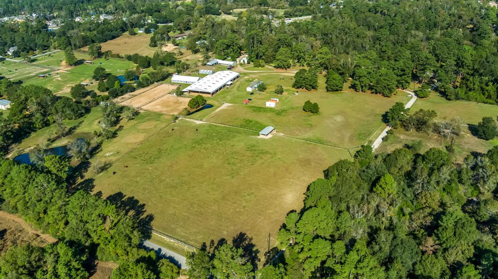 Discover this exceptional 30-acre horse property in Magnolia, designed for equestrian enthusiasts. With a 80' x 200' covered arena with 12 stalls attached, this estate is perfect for training and competitions. Additional features include two lighted 80' x 200' arenas, a 50' round pen, a pond for the horses to enjoy, and even a dedicated event building with a kitchen, equipped with multiple turnouts, and several bunkhouses for guests or camps. Explore miles of wooded trails, complete with streams and obstacles for trail course training. The property also includes a total of 25 spacious 12x12 stalls, 2 large barns, smaller barns for extra storage and a private pool for the guests and/or campers to use. The charming 2-bed, 2-bath home offers comfort with an office, bonus room, and a large covered carport. A true equestrian paradise!