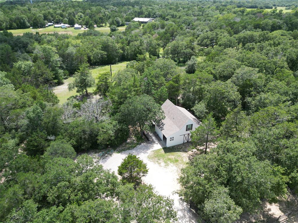 Tucked away in a peaceful wooded area near Round Top, this custom-built home exudes tranquility and charm. Completed in 2021, this home sits on 2.838 acres, offering a serene outdoor space with a covered patio and firepit overlooking the beautiful terrain, creek, and trails. The farmhouse features 17" high ceilings, shiplap walls, and stained concrete flooring, with an open floorplan & the primary bedroom downstairs. The kitchen features elegant East Quartz countertops and overlooks the serene outdoor creek terrain, with trails leading to the pasture.The upstairs loft and bedroom feature a separate staircase from the garage area, providing versatility for short-term rentals. With a convenient location between Houston and Austin, and close to Brenham's Blue Bell Creamery, this property perfectly blends nature and convenience. Ideal for those seeking a peaceful retreat with easy access to amenities.