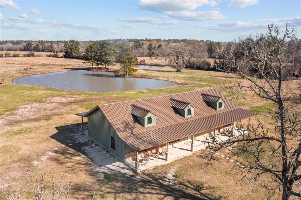 The spacious three bedroom, two bath home offers a modern farmhouse feel on 22.38-acres. From the welcoming front porch, you will be impressed when you open the front door to an oversized living area with open concept. The cathedral ceiling is trimmed out in beautiful wood with gorgeous ceiling fans. The kitchen is very attractive with quartzite countertops, tile backsplash, farmhouse kitchen sink, and the cook will appreciate the handy pot filler over the stove and whirlpool stainless appliances. The private primary suite has great windows, two walk-in closets, and a private bath with his and her sinks, separate tub, and a very nice tile shower. Two guest bedrooms share a full bath. The large back porch is the perfect place to sit and look at the beautiful lake, all you need is a couple of rocking chairs. The property has pretty pastureland and scattered trees and the home has spray foam insulation, metal purlings, luxury vinyl plank floors, metal roof, and beautiful upgrades.