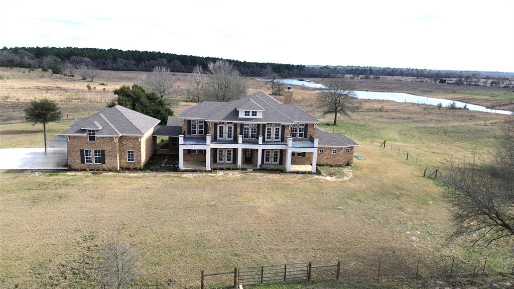 SPECTACULAR RANCH OPPORTUNITY AWAITS:GORGEOUS TWO STORY BRICK HOME ON 348.57 ACRES OF NATIVE PASTURE.THIS STUNNING HOME REVEALS THE CUSTOM CRAFTMANSHIP YOU WILL APPRECIATE. FROM THE HARDWOOD FLRS, HIGH CEILINGS, BRICK ACCENT, CUSTOM CABINETRY AND MORE. A GOURMET KITCHEN WITH AN ISLAND WORK AREA AND GAS COOKTOP, ALL STAINLESS, DOUBLE OVENS, BUILT IN MICRO, AND SUB ZERO FRI/FREEZER. A SMALL CRAFT/SUN ROOM, BREAKFAST AREA OFF THE KITCHEN, LRG FAMILY ROOM WITH WET BAR AND FIREPLACE. FORMAL DINING, BUTLERS PANTRY AND OFFICE/STUDY. LRG MASTERS SUITE COMPLETE WITH HIS/HER VANITIES, GARDEN TUB, OPEN WALK IN SHOWER AND SPACIOUS WALK IN CLOSET. SPIRAL STAIRCASE LEADS TO THREE BEDROOMS AND TWO FULL BATHS. THREE CAR GARAGE WITH TWO STORAGE CLOSETS AND A LARGE SECLUDED WALK IN SHOWER. 900 SQ FT BONUS AREA ABOVE. OUTDOORS FENCED OPEN PASTURES AND LRG LAKE WITH THREE PONDS ALL STOCKED. 100 AC OF TIMBER ON THE BACK OF THE PROPERTY. A LRG BARN AND SPACIOUS EQUIPMENT BARN AT 2ND ENTRANCE TO THE PROPERTY