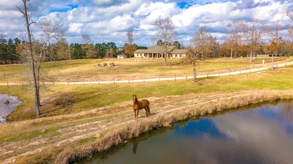 Stunning home sitting on 41+/- rolling acres overlooking three ponds!  Gated entry, Fenced, crossed fenced, working pens, huge shop, in ground swimming pool with attached covered entertaining area,  stone fire pit  to sit  around and watch the gorgeous  sunsets, covered front and back porches,  attached 3 car carport. Inside you will find a beautiful open concept rustic style home with split floor plan, vaulted ceilings, 3 oversized bedrooms 2 bath, office and large laundry room. Gorgeous double sided stone fireplace separating living room/den. This Gentleman’s ranch is a must see to appreciate, if your looking a peaceful country home for permanent living or a weekend getaway this it.  Ready for livestock, planting a garden, hunting and fishing! Just a short drive to Lufkin and a little  over and hour to Houston.