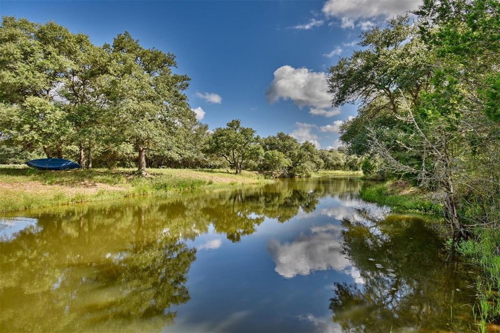 Stunning ranch in Sheridan is paradise found!  This fabulous 26.47 ac property is the perfect escape from the chaos of the day to day life.  As you drive into the property, weave thru a canopy of oak trees.  The elegant 2100 sf home is sure to please as you walk in the home, the entire front elevation is all windows, bringing the outdoors inside!  The décor’ is fabulous with a modern kitchen, custom cabinets, huge island w/plenty of storage.  Stainless steel appliances and gas double oven.  The beautiful master bedroom on 1st fl with ensuite bathroom with huge walk in accent shower.  On the 2nd floor, there is a great loft with a sitting/tv media viewing area.   Two spacious bd and bathroom.  Check out the composite deck overlooking the pond and relax in the incredible hot tub!  Other features: Sandy Creek is on the back with acreage continuing on the other side, ag exempt, water softener rainbird irrigation to flower beds, underground electricity.  So many features, just need to see!