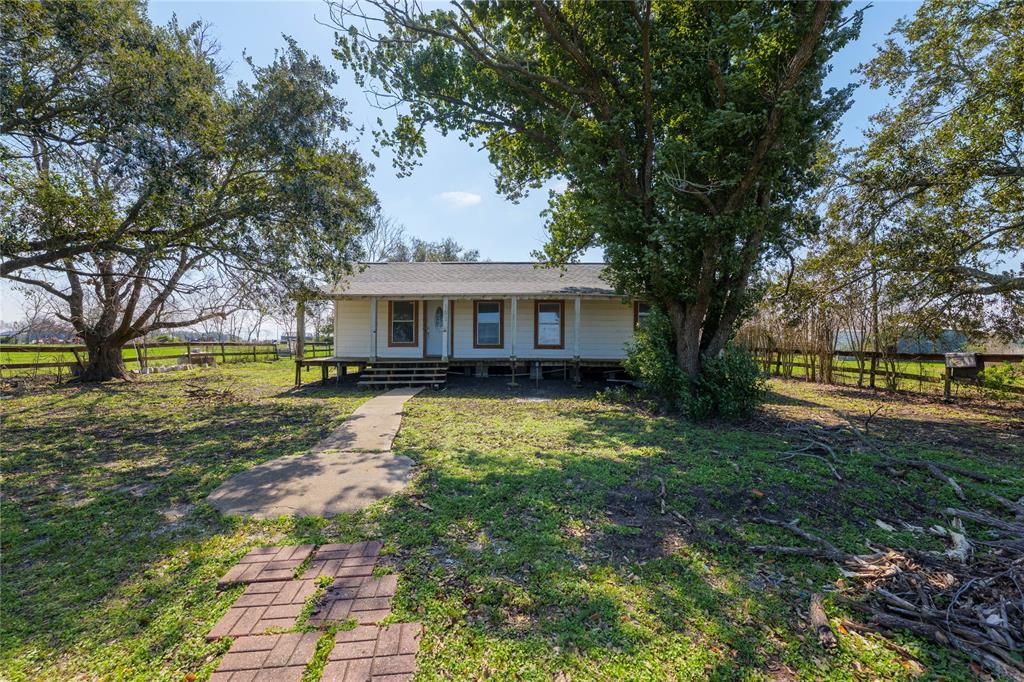 Country living on a private road with a farmhouse, barn, shop & acreage. The land features a completely fenced and gated 6 acres, pastures with Bahia Grass for your livestock, & mature trees. Outbuildings include: Stable Barn w/ 6 ample-sized stalls, & a large workshop.The house is spacious with a great room floor plan: kitchen, dining & living all open to each other with a wall of windows, an extra front room, with front and back porches the length of the home. Many improvements: Beautiful new vinyl plank flooring throughout in 2020, recent new roof, new plumbing underneath home, Central HVAC replaced in 2021, foundation leveled, new fencing on one side and roof cap on barn. The primary bath was completely redone with separate shower, freestanding tub & double sinks. Peaceful area with gorgeous sunset views from the living area. It just needs paint and some more updates to make it your own. Many costly repairs & improvements were done. Close to the fair grounds/arena & Matagorda Bay.