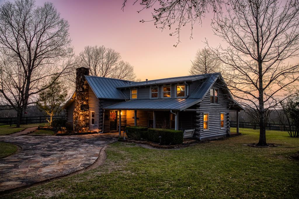 Nestled on +/-36 breathtaking acres of rolling terrain, this stunning ranch offers the perfect blend of rustic charm and modern comfort. The modern log cabin is designed for both elegance and relaxation, featuring an open-concept layout with soaring ceilings and large windows that fill the space with natural light, creating an airy and bright ambiance. A cozy stone fireplace serves as the focal point of the living area, perfect for gathering on cool evenings. Step outside to the inviting pool overlooking a fully stocked pond, offering serene views and a perfect place to unwind. The beautifully landscaped property includes a large shop/barn with working pens, ideal for ranching or equestrian use, and a newly renovated guest quarters, perfect for visitors or additional living space. With easy access to Highway 290, commutes to Houston and nearby Brenham are a breeze, making this the ultimate country retreat for a quick escape from the city. *Additional details/buyers guide upon request*