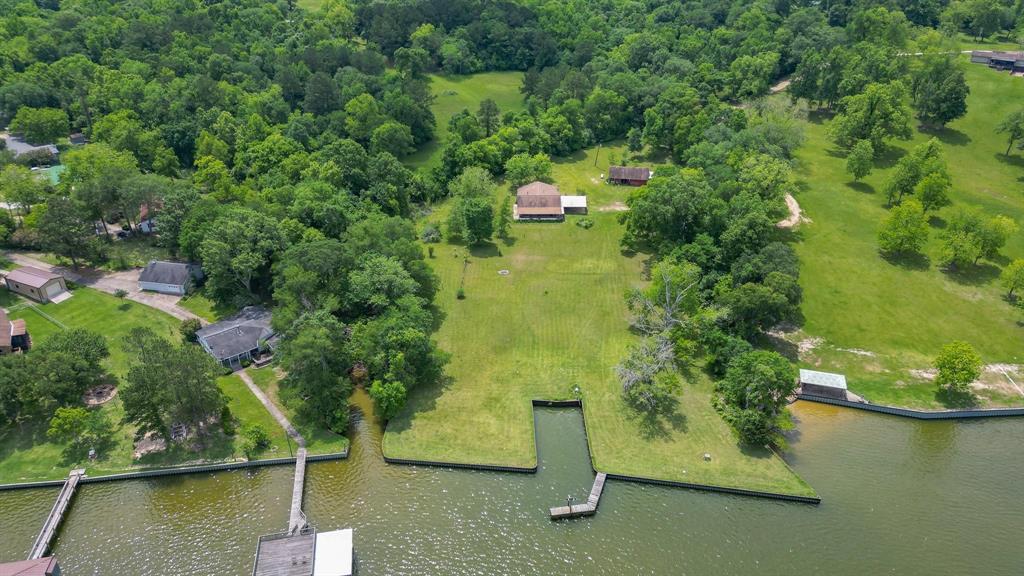 4.26 acre private lakefront property with metal bulkhead and boat slip. Not in a subdivision. There are very few like this remaining this side of Lake Livingston. Property is NOT anywhere near the dam spillway and has never flooded. Private road means privacy and more security and a perpetual easement onto this property. New roof on main house. House needs updates but is livable now. All appliances convey. 40' covered front porch overlooking lake. Extra large carport at house. Detached garage has 3 bays and tons of workshop space with huge workbench, total of 971 sq ft! Additional parking for RV, boat, trailer. Additional storage next to garage. Hunting and fishing allowed. This property has been enjoyed by 5 generations. Make your own memories here now.