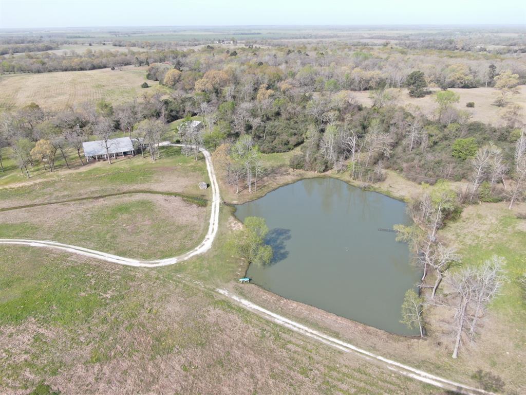 Seldom does a listing such as this come on the market. Located on the historic SH 21 halfway between Madisonville and Crockett (Austonio) and in the Lovelady ISD. You enter the property and continue down a long drive that opens up into a beautiful open pasture with scattered oaks, a nice lake with a remarkable view of the main home on one hill a cabin across the lake on another hill. The 3 BR, 2.5 bath home is gorgeous with hardwood flooring throughout and huge porches overlooking the property. The home seems to have never seen an untidy day. As you walk in the front door it opens to a large great room with a woodburning fireplace and the large kitchen and dining area. The huge porches seem to be the gathering place to watch the deer and wildlife. Also included is a 30' X 50' shed for additional parking and storage.  Deer stands & feeders stay. Don't miss out on this exceptional property.