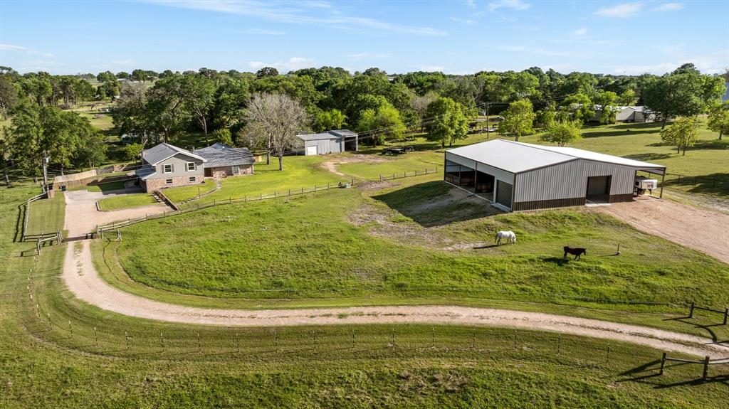 2355 Jackson League Circle Brenham, Texas Live your American Dream with horses, cows, & more on an 11.7-acre ranchette in Brenham, TX. This 3,594 SF home offers 4/5 bedrooms, 3.5 baths, & a thoughtful mix of vintage country charm and modern updates. Features include a metal roof, spacious kitchen with granite island, potbelly stove, walk-in appliance pantry, living room with bay window, and a primary suite with renovated bath, multiple closets, and French doors leading to the pool and deck. Upstairs includes a second primary option, two additional bedrooms, and large office. Lower lounge offers a bar area, built-ins, and brick fireplace. Recent updates include new windows, gutters, & upstairs electrical, plumbing, & HVAC. Outside, enjoy a pool, large workshop, 4,875 SF barn/stable with extra-large stalls, 10,400 SF dirt riding arena, cattle barn, pond, chicken coop, and mature oaks, pecans trees, & 2 pines. Pool house provides extra storage. Cross-fenced with electric fencing. A true country retreat ready to welcome you home!