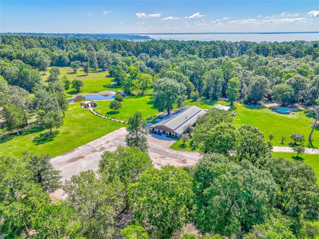 Nestled on approximately 11.2 acres of picturesque land just minutes from Lake Livingston, this stunning 4,000 sq ft building offers endless possibilities. Perfectly versatile, it can be transformed into a 3-5 bedroom home with 2 bathrooms and a full kitchen. The property features 10 mobile home spots, making it ideal for a mobile home park or a new homes subdivision. Its prime location on a busy highway provides excellent visibility and accessibility, ideal for a residential or commercial venture. Outdoors, enjoy a massive 1,500 sq ft covered porch, a 1,000+ sq ft deck, and a peaceful outdoor ceremony area overlooking a tranquil pond. Whether you're looking to develop a residential community, establish a business, or enjoy private living in a scenic setting, this property offers exceptional potential. Don’t miss the opportunity to own this versatile, scenic property with fantastic amenities and location.