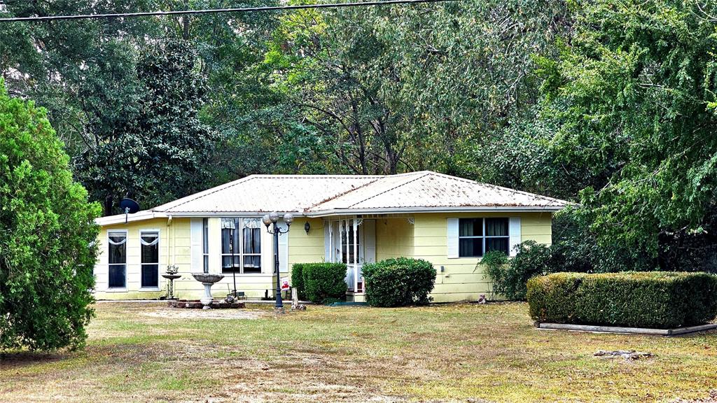 This is a cute older house with an outbuilding that could easily be an office or schoolhouse.  The house needs some work but is livable.  It is being sold "AS IS". Room dimensions are approximate.  Please verify.  The property is owned by an estate.  The yard is very pretty, particularly in the back as it adjoins a nice, wooded area and a larger tract. Very close to Lake Livingston!
