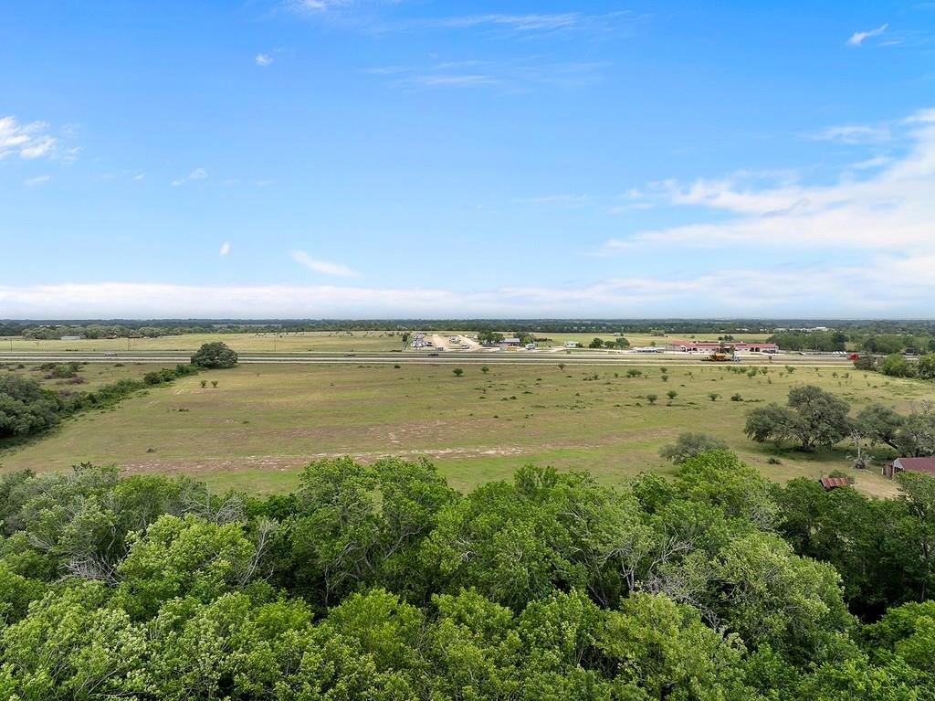 Prime Commercial Opportunity with I-10 Frontage! Unlock the potential of this exceptional 33.92-acre tract located directly off Interstate 10, featuring approximately 1,100 feet of high-visibility feeder road frontage. Currently benefiting from an agricultural exemption, this partially wooded property presents a rare and versatile opportunity for commercial development. Significant infrastructure upgrades are underway, including a new westbound exit near County Road 210 for traffic coming from Houston and a new overpass to accommodate southbound traffic from San Antonio. Additionally, the widening of I-10 to six lanes will further enhance accessibility and long-term value. Ideally positioned within 1.5 hours of Houston, Austin, and San Antonio, this location offers tremendous reach to three of Texas’s largest markets. According to TXDOT AADT data, the site benefits from an average daily traffic count of approximately 38,000 vehicles—ensuring high visibility and consistent exposure.