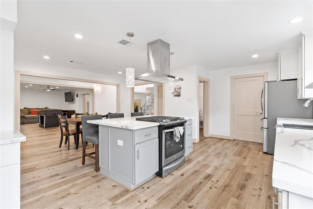 Your thoughtfully designed kitchen flows seamlessly into the dining and living areas, creating an open, inviting space for gatherings. The oversized island with built-in cooktop doubles as both a prep station and casual dining hub, highlighted by modern pendant lights. Sleek quartz countertops, custom cabinetry, and stainless steel appliances add a contemporary touch, while sightlines to the adjacent living room enhance the home’s open-concept layout.