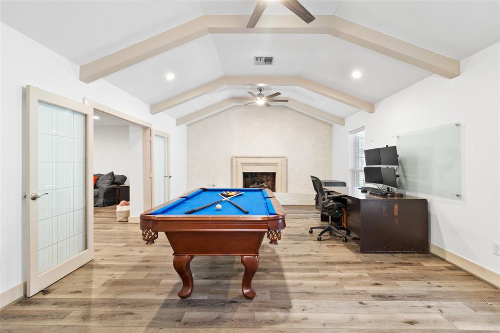 Your spacious lower-level flex area features soaring vaulted ceilings with exposed beams, creating an open, airy feel. The framed fireplace adds warmth and elegance, while large windows allow natural light to flow in. Double glass-paneled doors connect seamlessly to the living area. This versatile room is perfect for relaxing, entertaining, or customizing to your needs.