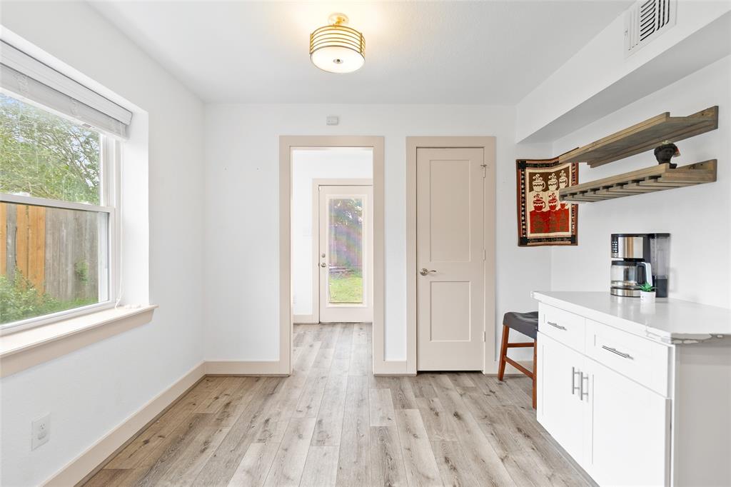 Take a glance at your sunlit corner of the home that is perfect as a coffee bar, reading nook, or mudroom. A large window fills the space with natural light, while the door provides easy access to the backyard. Floating shelves and built-in cabinetry offer display and storage options, complemented by stylish wood-look flooring that flows seamlessly throughout the home.