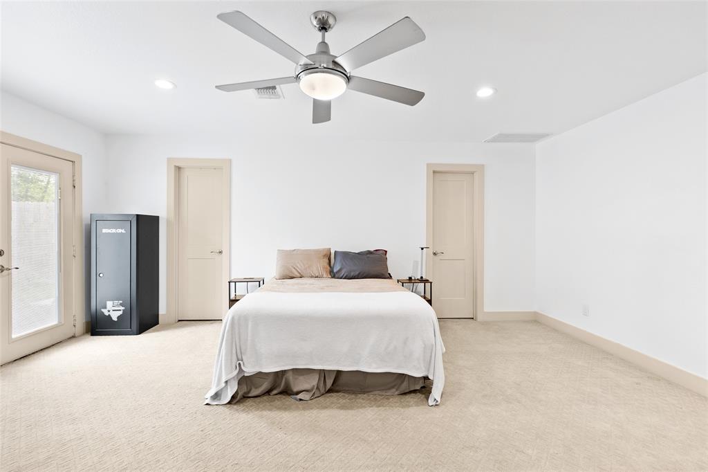 In your primary bedroom, a neutral palette and recessed lighting create a bright, inviting atmosphere. Soft carpeting adds warmth, while a modern ceiling fan ensures comfort. Two doors lead to a spacious walk-in closet, and beyond, your private ensuite bathroom awaits. French doors open to the backyard, offering natural light and a private outdoor retreat.