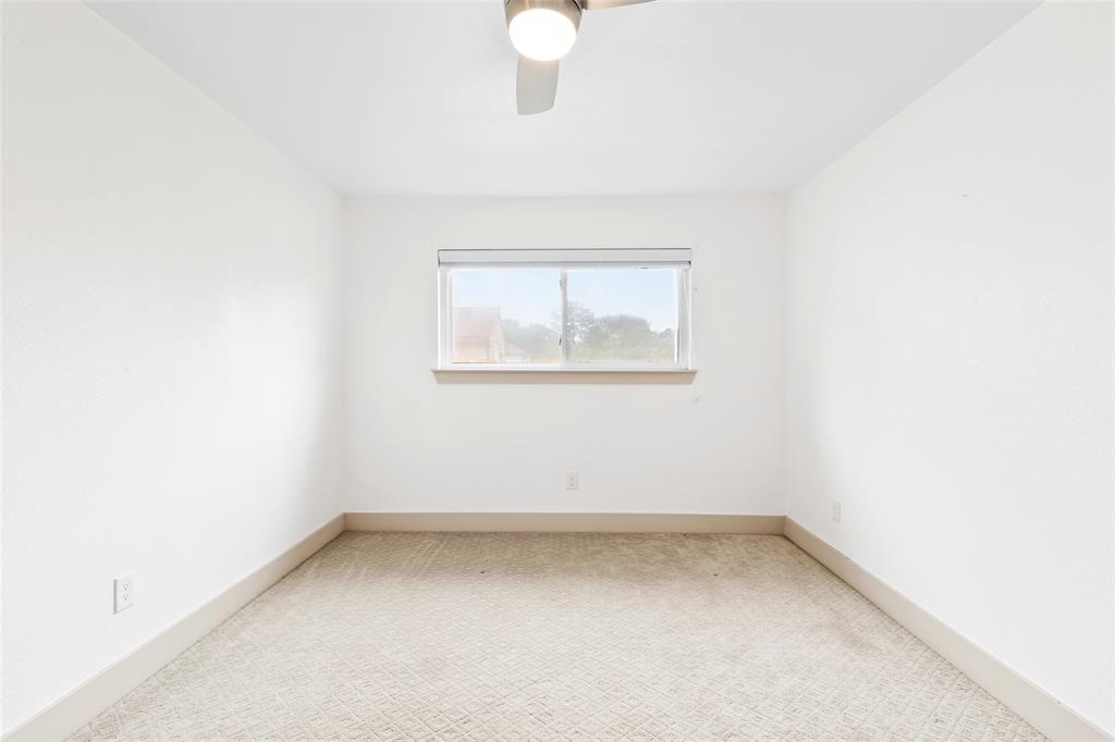 Your light-filled secondary bedroom offers a calm, neutral setting with plush carpeting and a wide window that lets in soft, natural light. A modern ceiling fan ensures comfort, while the simple layout invites personalization as a guest room, office, or creative space.