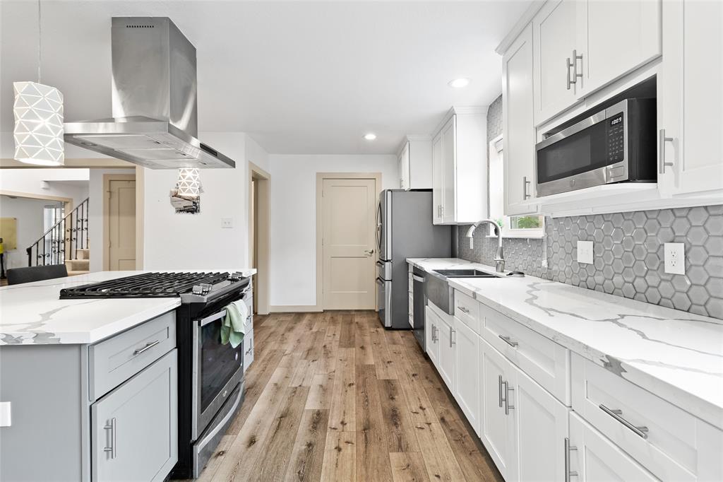 Your kitchen blends modern design with everyday function—quartz countertops, white cabinetry, and a bold geometric backsplash add style and personality. Stainless steel appliances, under-cabinet lighting, and a window over the sink brighten your routine while keeping the space efficient and inviting.
