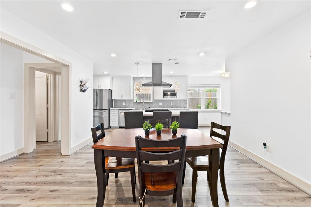 Your inviting kitchen features white cabinetry, stainless steel appliances, and a textured backsplash for a clean, modern feel. Pendant and recessed lighting keep it bright, while a large window offers backyard views. The open layout flows into your informal dining room, perfect for everyday meals and easy entertaining.