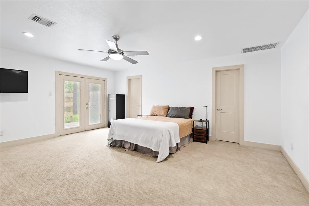 Enter your primary bedroom nestled on the first floor. Complete with soft neutral carpeting, recessed lighting, and a sleek ceiling fan for year-round comfort. French doors open to the backyard, filling the room with natural light and offering a private outdoor entrance. Dual interior doors lead to your en-suite bath and spacious walk-in closet, providing both convenience and comfort.