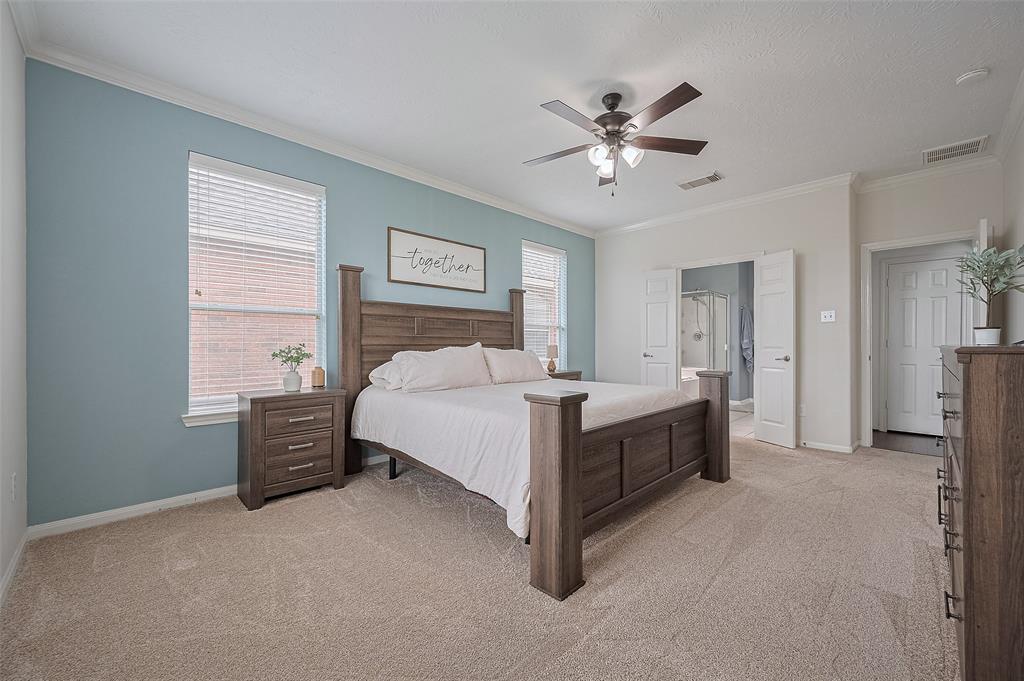 A cozy and spacious primary bedroom with soft carpet, tray ceiling, and a private entrance to the bathroom suite.